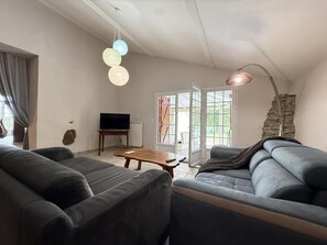 A living room with a sofa, a coffee table, a TV, and a stone accent wall.
