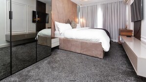 Una moderna camera d'albergo con un letto grande, un divisorio in vetro, una TV a schermo piatto e una parete decorativa in legno.