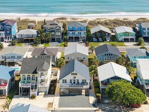 A coastal residential area with houses, some with balconies, and a beach in the background.