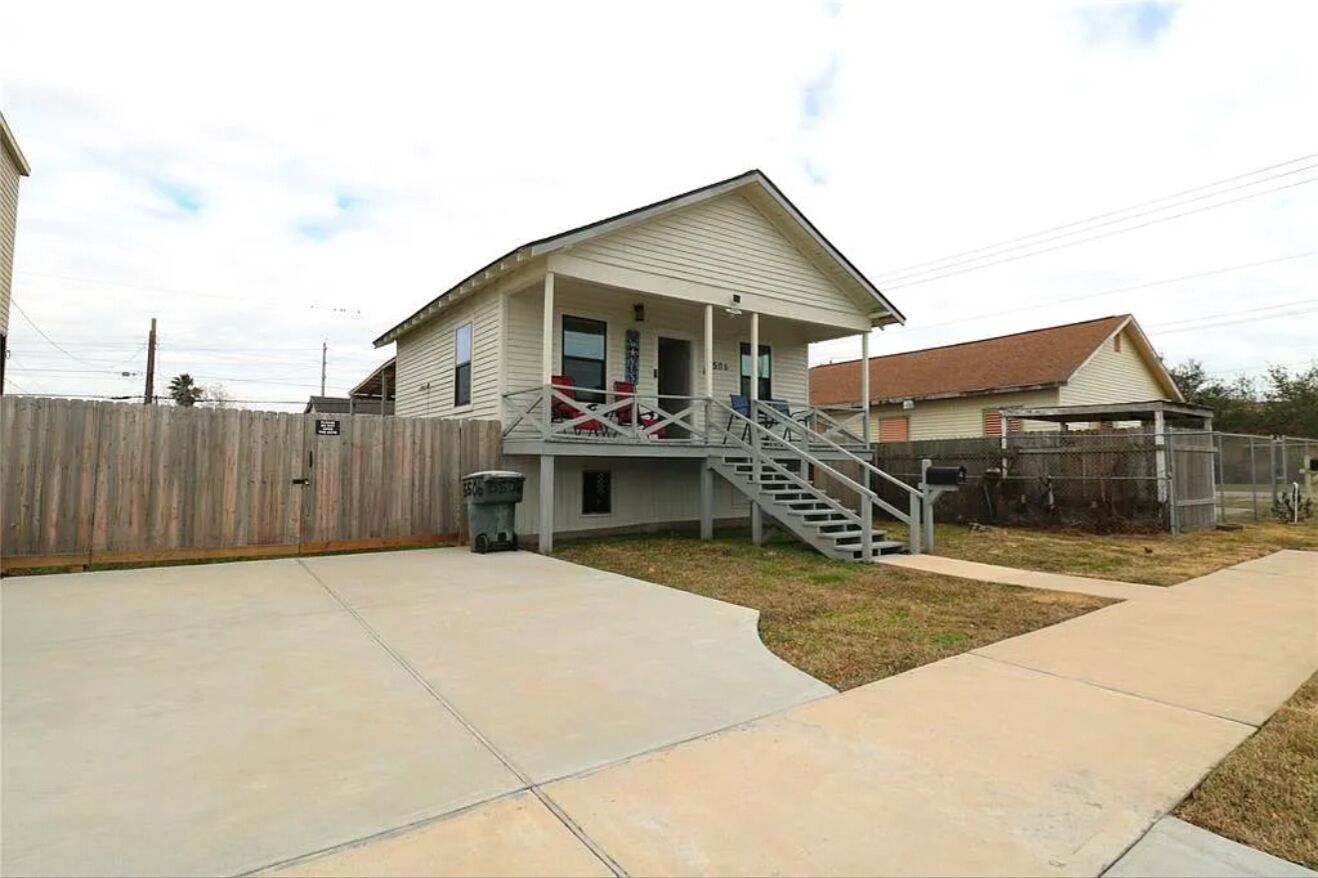 A single-story house with a front porch, a staircase leading to the entrance, and a fenced backyard.