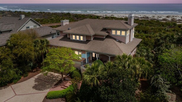 Ein zweistöckiges Haus mit einem großen Balkon mit Blick auf Strand und Meer.
