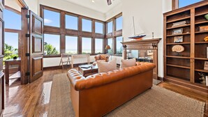 Ein geräumiges Wohnzimmer mit einer Ledersofa, Holzbücherregalen und einem großen Fenster mit Blick ins Freie.