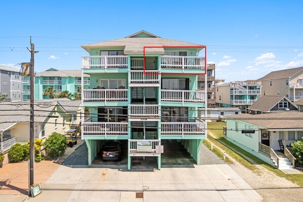 A multi-story building with balconies and a garage. - Top-Floor Canal View Condo w/ Pool, Steps to Beach (Carolina Beach)