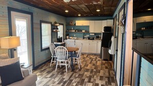 Una cocina acogedora con pisos de madera, armarios blancos y un comedor con mesa y sillas.