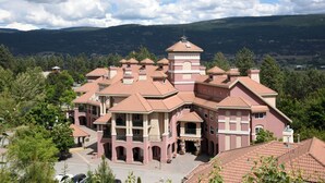 Um edifício grande, com vários andares, fachada simétrica, múltiplas varandas e uma torre central.