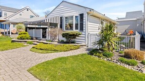 A single-story house with a front porch, a small garden, and a white picket fence. - 3BR Home - Close to Beach - Backyard Oasis (Margate City)
