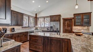 Una cocina amplia con armarios de madera oscura, encimeras de granito y una isla grande.