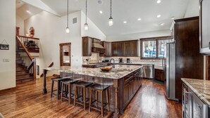 Una cocina amplia con una isla grande, piso de madera y electrodomésticos modernos.