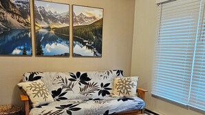 Ein Wohnzimmer mit einer Couch, einem Couchtisch und Holzböden. An der Wand hängen drei gerahmte Bilder.