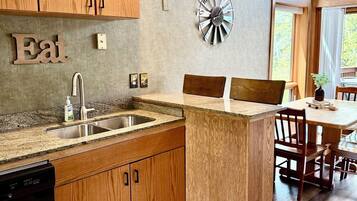 A modern kitchen with wooden cabinets, a granite countertop, and a built-in dishwasher.