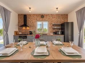 Un coin repas avec un mur en briques, un poêle noir et un réfrigérateur.
