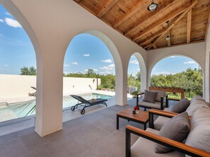 Un espace extérieur abrité comprenant une piscine, des chaises longues et un plafond en bois.