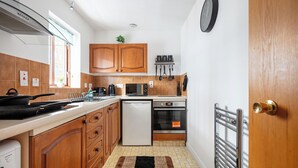 A compact kitchen with wooden cabinets, a microwave, a dishwasher, and a built-in oven.