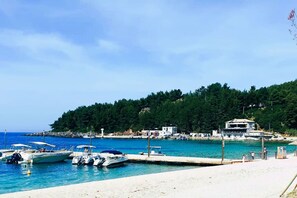 A coastal marina with boats docked, a sandy beach, and a hillside with buildings. - Philoxenia Village House (Himare)