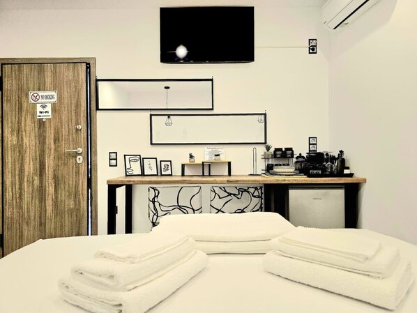 Ein Hotelzimmer mit Bett, Schreibtisch, Computer, Fernseher und einer Tür mit Rauchverbot-Hinweis.