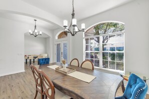 Une salle à manger avec une table en bois, des chaises et un lustre.