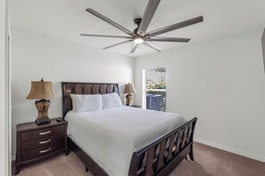 A bedroom with a bed, nightstands, lamps, a ceiling fan, and a window with blinds. - Luxury Escapes Home W/ Heated Pool  Near IMG & Siesta Key  Beach (Bradenton)