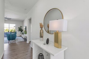 Un intérieur moderne avec une console blanche, un miroir à cadre doré et une lampe blanche.