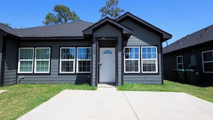 A two-story house with a front door, multiple windows, and a small porch area.