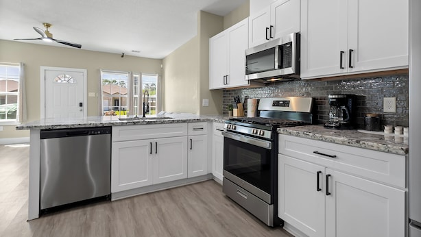 A modern kitchen with white cabinets, stainless steel appliances, and a granite countertop.
