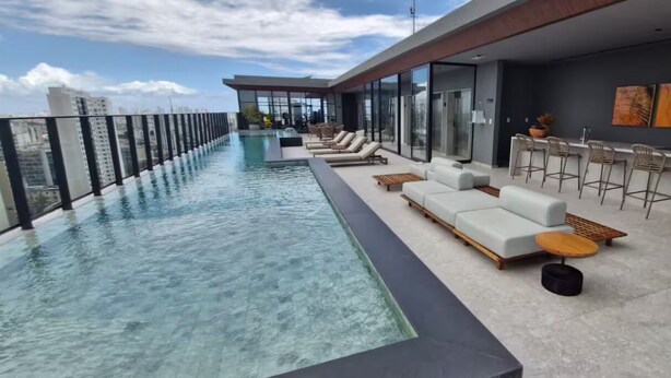 A rooftop infinity pool with a modern bar area and seating. - Charm and Sea View in the Vitoria-Alive Corridor (Vitória Salvador)