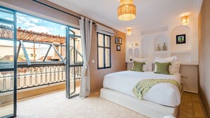Un dormitorio con una cama grande, un balcón con vistas y una araña.