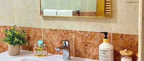 A bathroom with a large mirror, a sink, and toiletries.