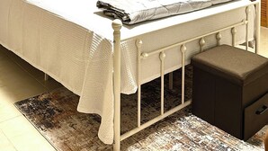 Quarto com cama, mesa de cabeceira, abajur, ventilador de teto e armário.