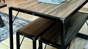 Quarto com uma mesa de madeira, televisão fixada na parede e porta com persiana de madeira.