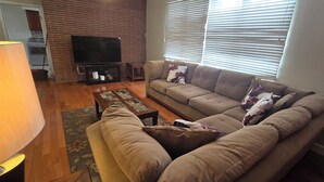 A living room with a sofa, a coffee table, a TV on a stand, and a window with blinds. - Spacious 3-bedroom apartment in charming Philadelphia with AC, WiFi (Philadelphia)