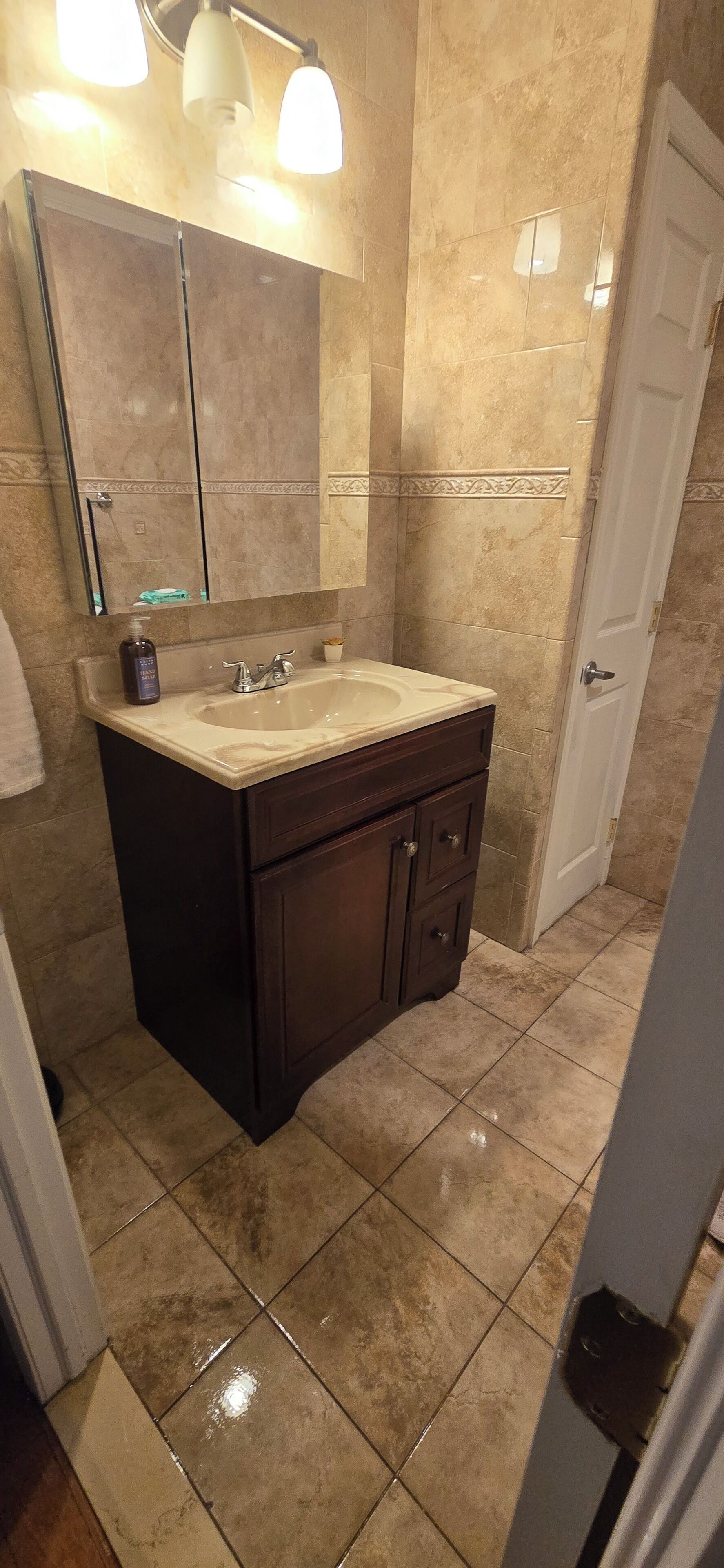 A bathroom with a sink, mirror, and cabinet.