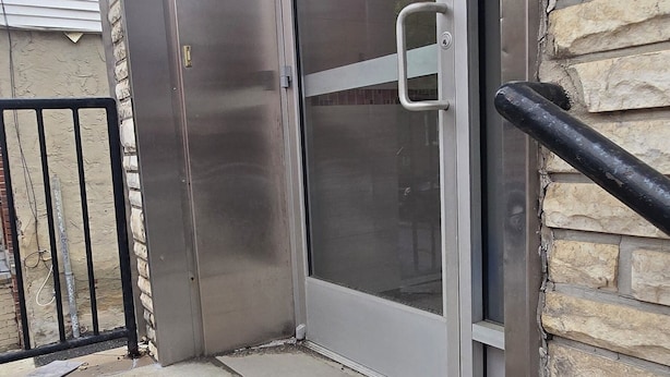 A building entrance with a glass door, a metal handrail, and a stone wall. - Spacious 3-bedroom apartment in charming Philadelphia with AC, WiFi (Philadelphia)