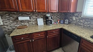 A kitchen with wooden cabinets, a granite countertop, a coffee maker, a toaster, and a dishwasher. - Spacious 3-bedroom apartment in charming Philadelphia with AC, WiFi (Philadelphia)