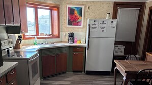 A kitchen with wooden cabinets, a refrigerator, a sink, and a window. - Beautiful Century old Apartments-Apt B (Algoma)