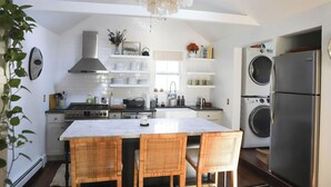 Une cuisine moderne dotée d’un îlot central, d’appareils électroménagers intégrés et d’un luminaire suspendu.