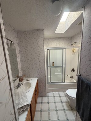 Un bagno con doccia, WC e lavandino.