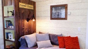 A cozy room with a wooden bookshelf, a framed picture on the wall, and a bed with pillows.