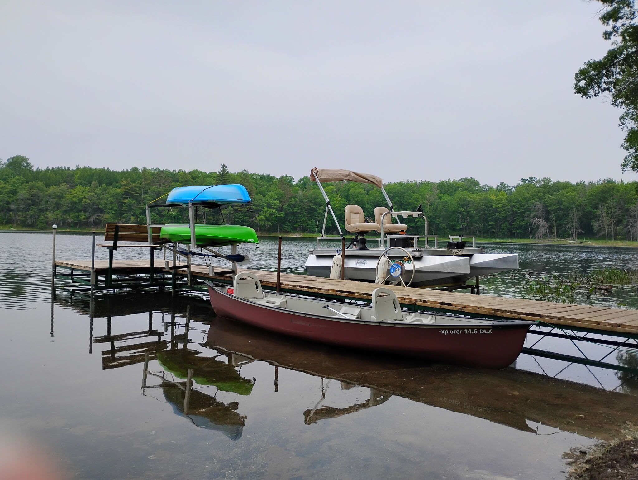A dock with a small boat, a bench, and a covered seating area.
