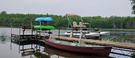 A dock with a small boat, a bench, and a covered seating area.