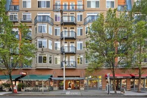Un edificio residencial de varios pisos con balcones, fachada de ladrillo y locales comerciales en la planta baja.