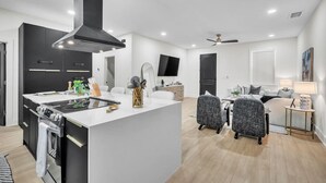 A modern kitchen with a central island, black cabinetry, and a built-in stove.