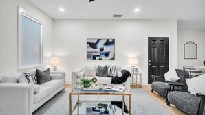 A modern living room with a grey sofa, a coffee table, and a black door.