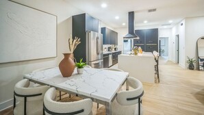 A modern kitchen with dark cabinets, a marble countertop, and a central island.