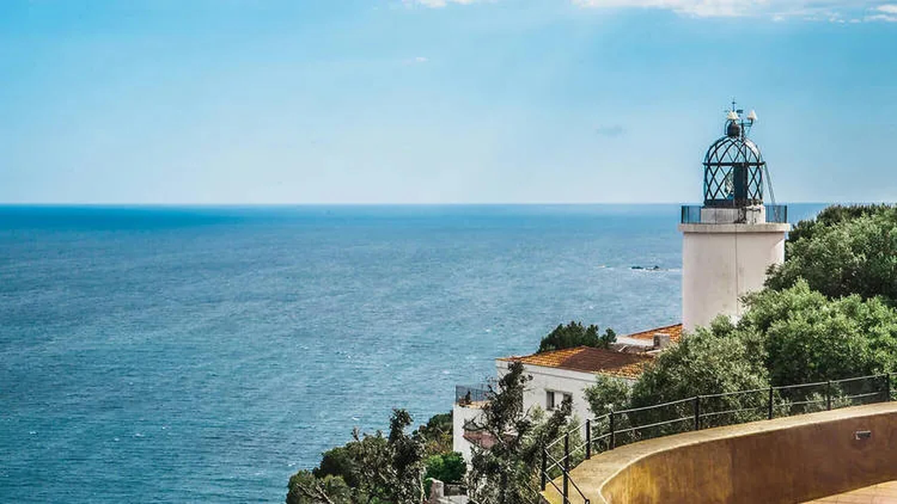 A coastal building with a lighthouse, overlooking the sea.