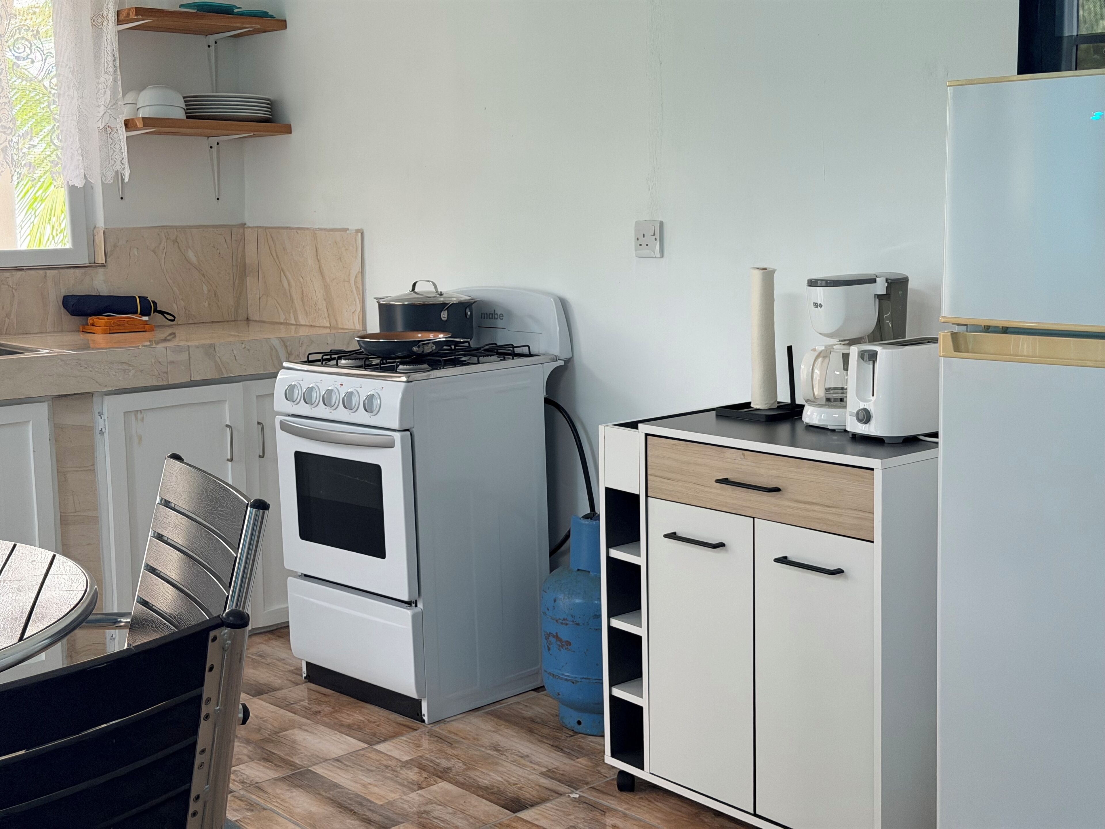 Et lille køkken med komfur, ovn og en bordplade med kaffemaskine og brødrister.