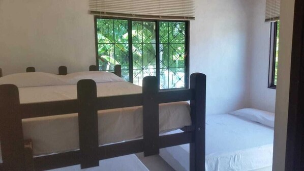 A room with a bed, a window with a view of greenery, and a small table.