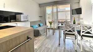 A modern kitchen with a microwave, coffee maker, and a dining area with a table and chairs. - La Palmeraie by Interhome (Les Mathes)