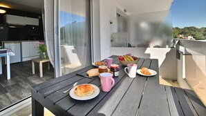 A balcony with a dining table set with food and drinks, a chair, and a view of the surrounding area. - La Palmeraie by Interhome (Les Mathes)