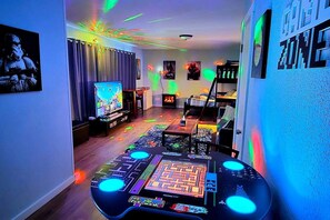A gaming room with a large screen, a gaming table, and colorful lighting. - Diamond Point~Canal Views! Peaceful with Game Room (Sequim)