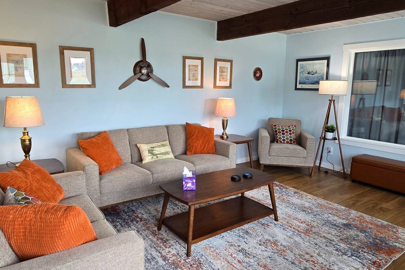 A living room with a sofa, armchairs, a coffee table, and a ceiling fan.